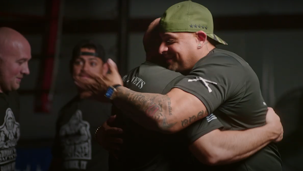 two veterans hugging with two veterans in background