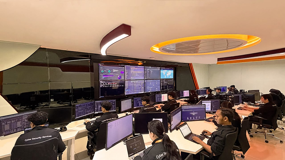 A modern, high-tech operations workplace with multiple computer monitors and personnel working at desks