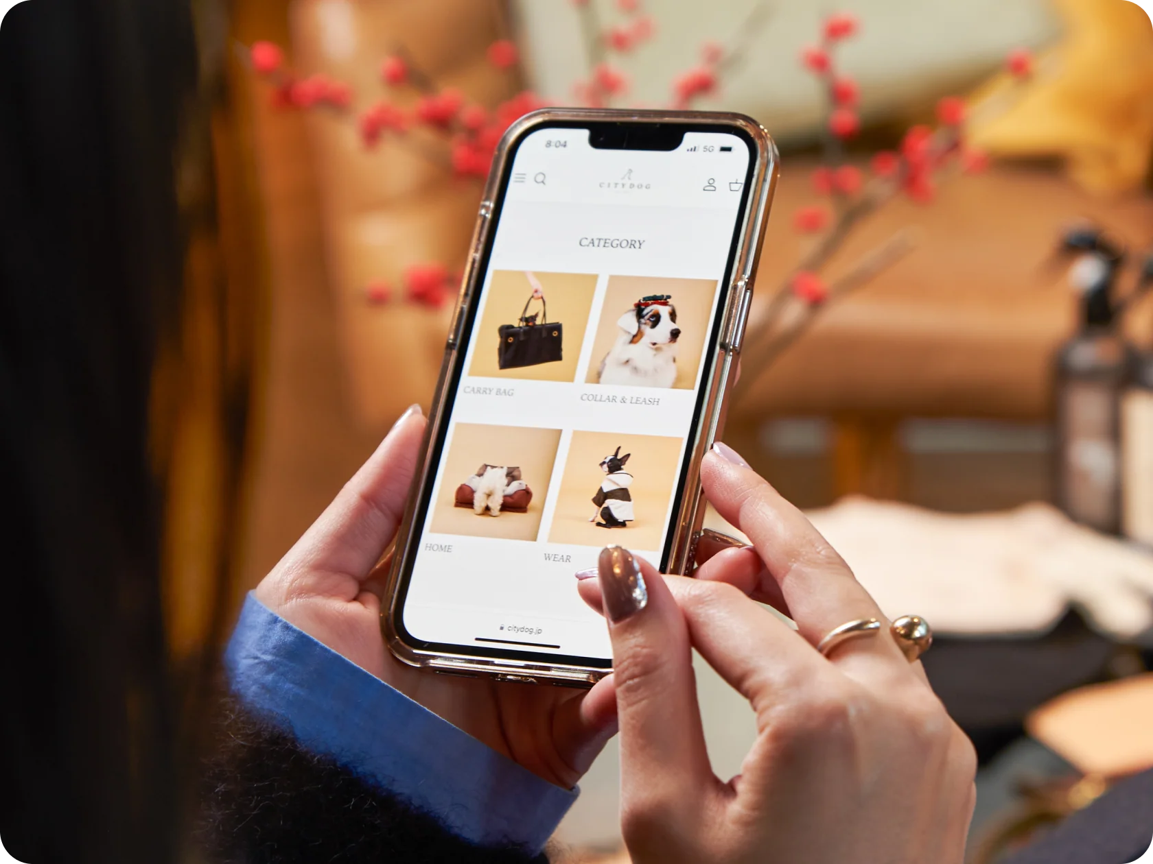 A woman holding a smartphone with shopping categories open on it