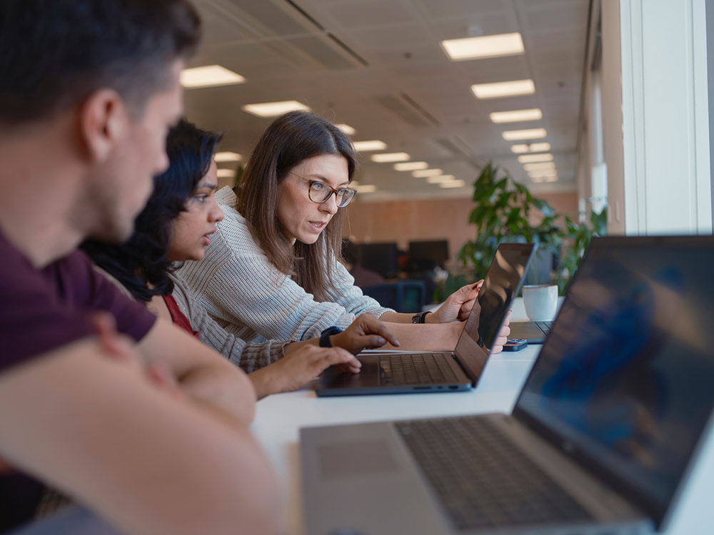 Two women and a man looking at the laptop screen