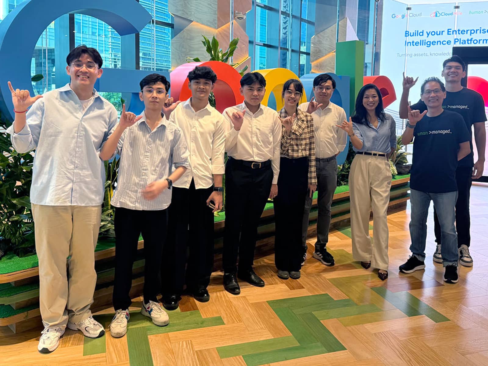 Group posing with shaka signs in front of Google logo