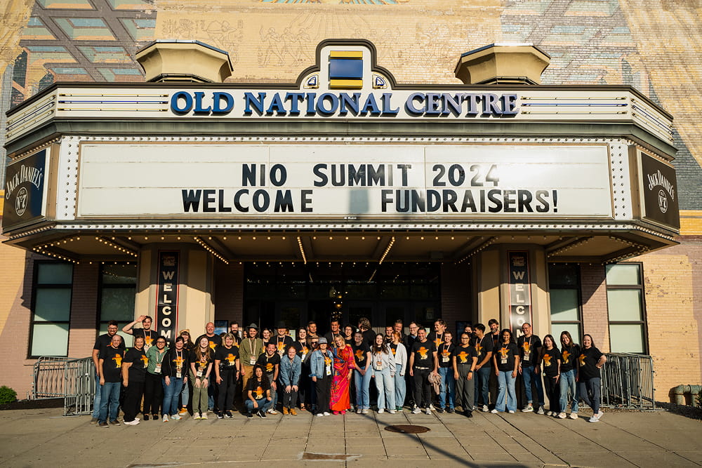 Group of fundraisers under 'NIO SUMMIT 2024' sign