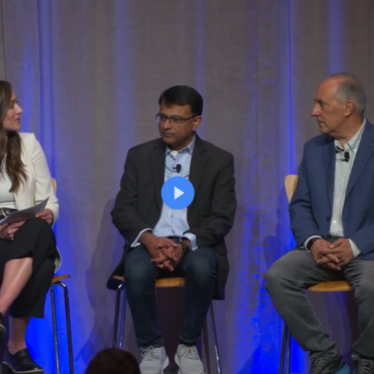 ステージに座って話している女性と 2 人の男性の画像