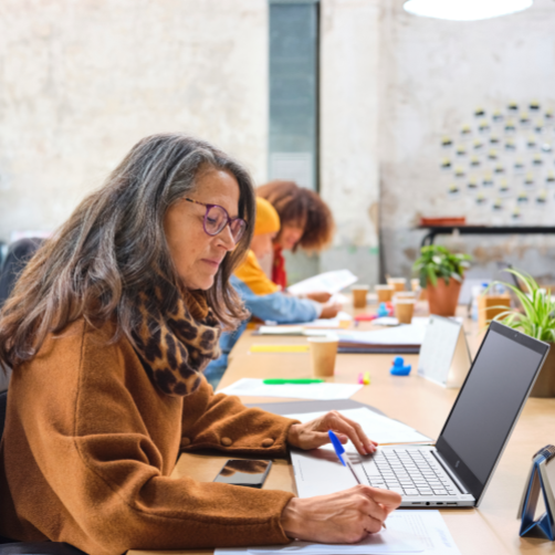 ノートパソコンで作業している白髪の女性の写真