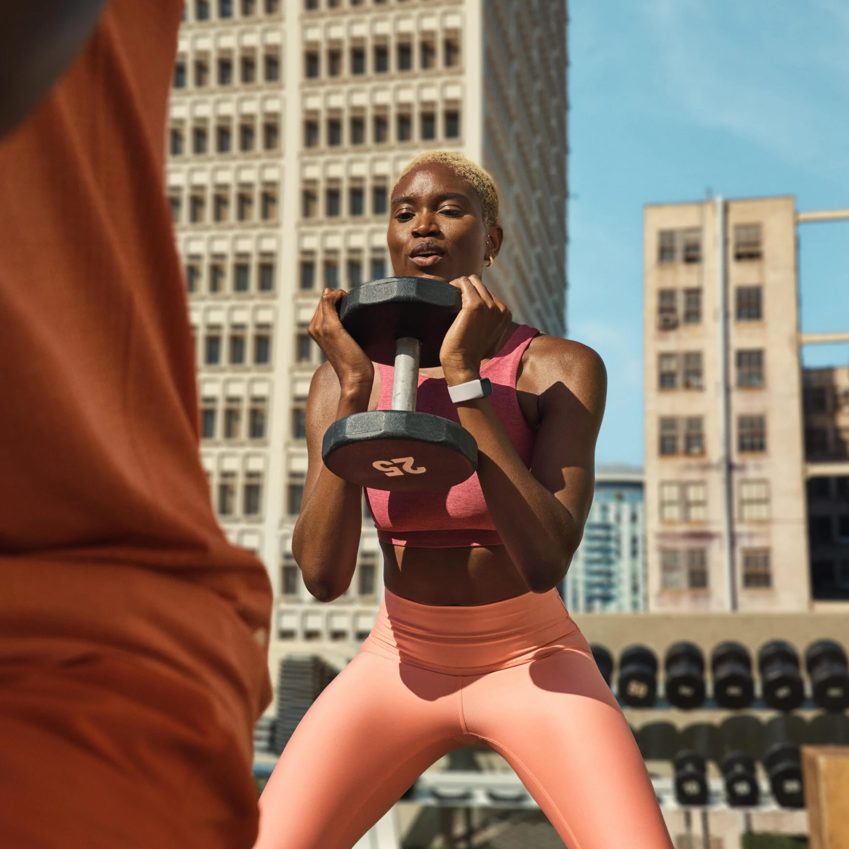 Image of woman lifting weights wearing Google Fitbit air
