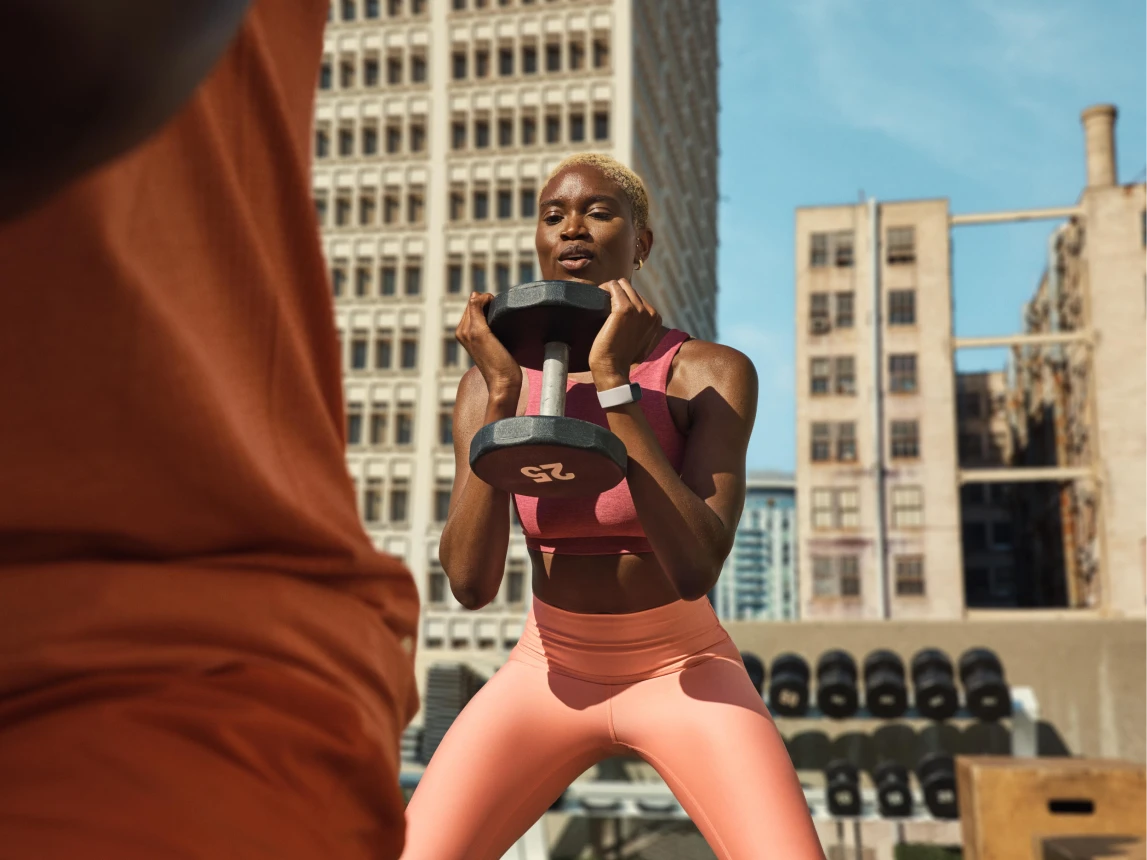 Image of woman lifting weights wearing Google Fitbit Air
