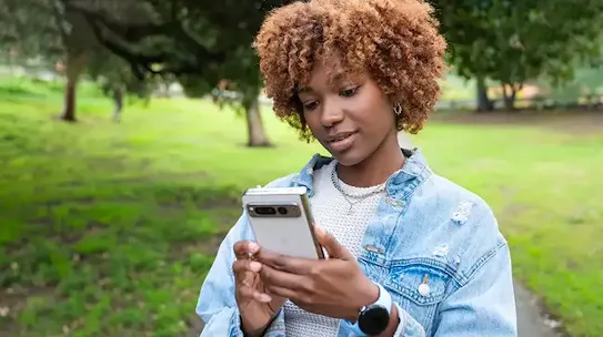 Woman standing in a park looking at her Android phone
