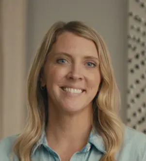 A smiling woman with blonde wavy hair wearing a denim shirt, appearing in a professional portrait for a Louisiana Crawfish Company case study.