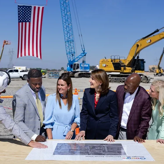 Person points to a Google West Memphis map for observing officials, with heavy construction equipment on site.