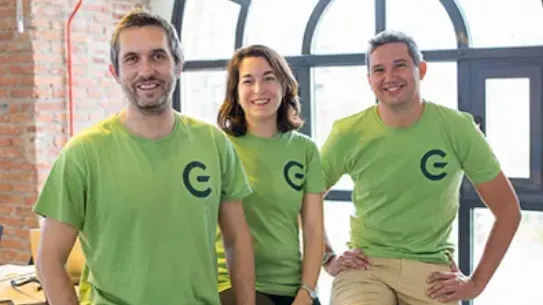 The GreeMko cofounders are wearing matching green shirts with their startups’ logo and smiling at the camera.