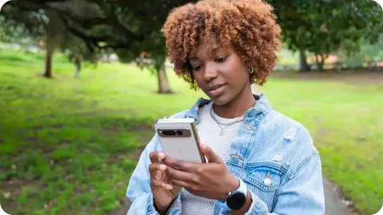 Woman standing in a park looking at her Android phone