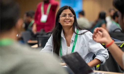 A woman wearing green lanyard looking at someone.