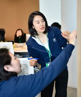 2人の女性がホワイトボードを囲んでアイデアを話し合っている。1人は書き込みをしている。