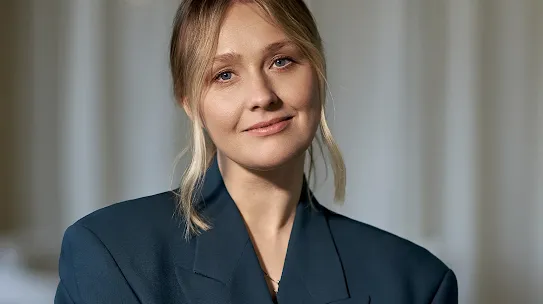 A professional headshot of a blonde woman with blue eyes, wearing a dark teal blazer, smiling softly against a blurred neutral background. Featured in the "From Crisis to Digital Power" report regarding EU digital policy.