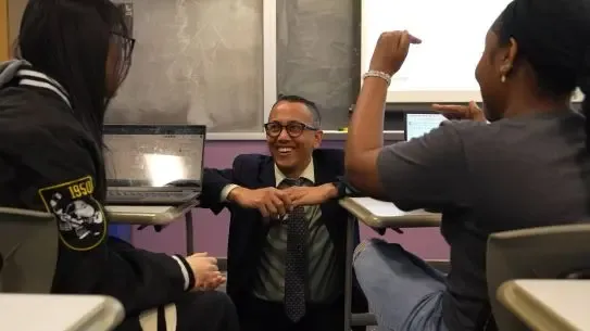 SUNY professor speaks to two students at the front of a lecture hall