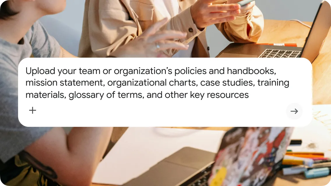 A UI overlay of a white instructional text box on a background photo of two colleagues collaborating at a wooden table with a laptop and documents. The text box reads: "Upload your team or organization’s policies and handbooks, mission statement, organizational charts, case studies, training materials, glossary of terms, and other key resources." The interface features a plus icon for adding files and an arrow-right icon for submission.