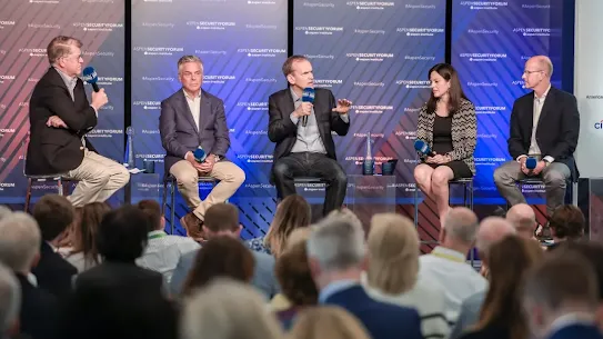 Kent Walker, President of Global Affairs at Google & Alphabet (center), gestures while speaking on a panel at the 2024 Aspen Security Forum. He is joined by four other experts on stage in front of a blue audience and a backdrop featuring Aspen Security and Aspen Institute branding.