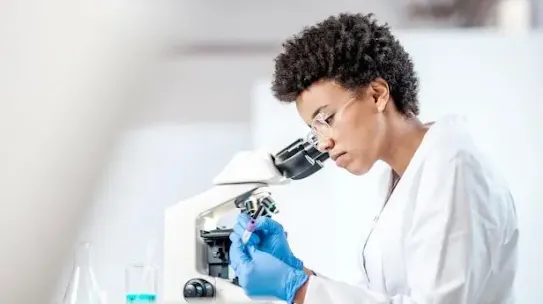 Medical professional using microscope and research technology