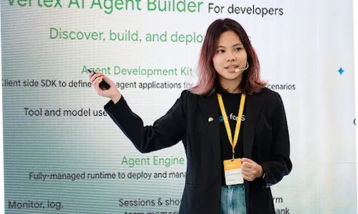 A female speaker at an event, standing in front of a Vertex AI Agent Builder presentation slide.