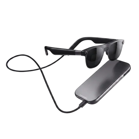 Black XREAL AURA wired XR glasses connected by cable to a companion device.