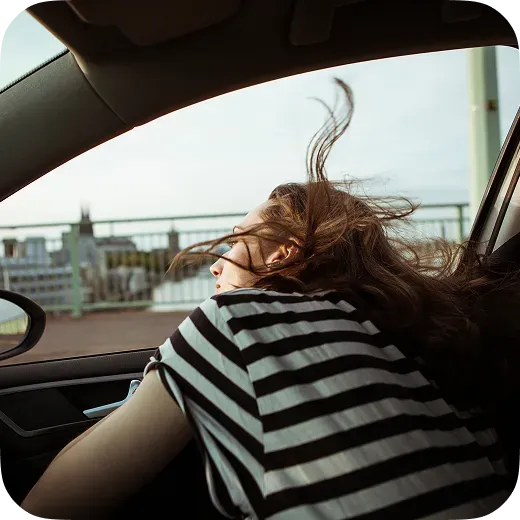 Woman leaning out a passenger car window during a road trip representing personalized navigation with Waze