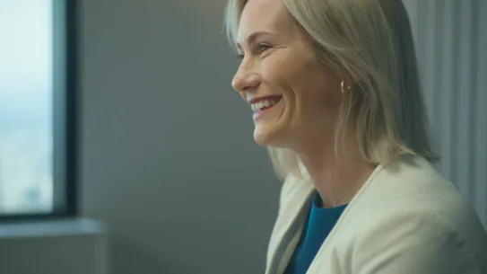 Side-view of a person smiling at someone off-screen.