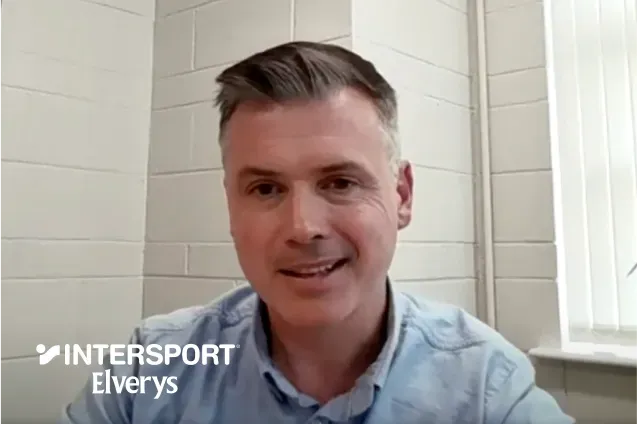 A headshot of Liam Lennon, Head of Online & Digital Marketing at Intersport Elverys, during a video testimonial. He is wearing a light blue button-down shirt and is positioned against a white brick wall. The Intersport Elverys logo is overlaid in the bottom-left corner.A headshot of Liam Lennon, Head of Online & Digital Marketing at Intersport Elverys, during a video testimonial. He is wearing a light blue button-down shirt and is positioned against a white brick wall. The Intersport Elverys logo is overlaid in the bottom-left corner.