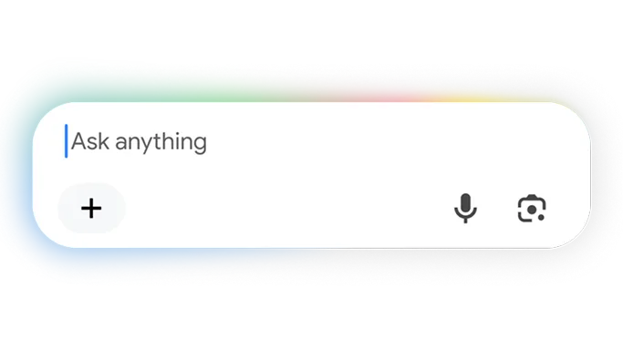 A close-up of a rounded, white conversational search bar with the placeholder text "Ask anything" and a blue cursor. The top edge of the bar features a soft, multi-colored glow in Google's signature blue, red, yellow, and green colors. Inside the bar, there is a plus sign icon on the left, and a microphone icon and a Google Lens camera icon on the right.