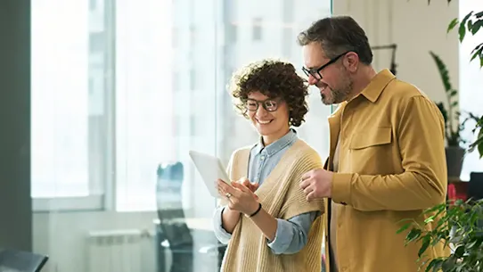 Two work colleagues reviewing information on a tablet at the office.