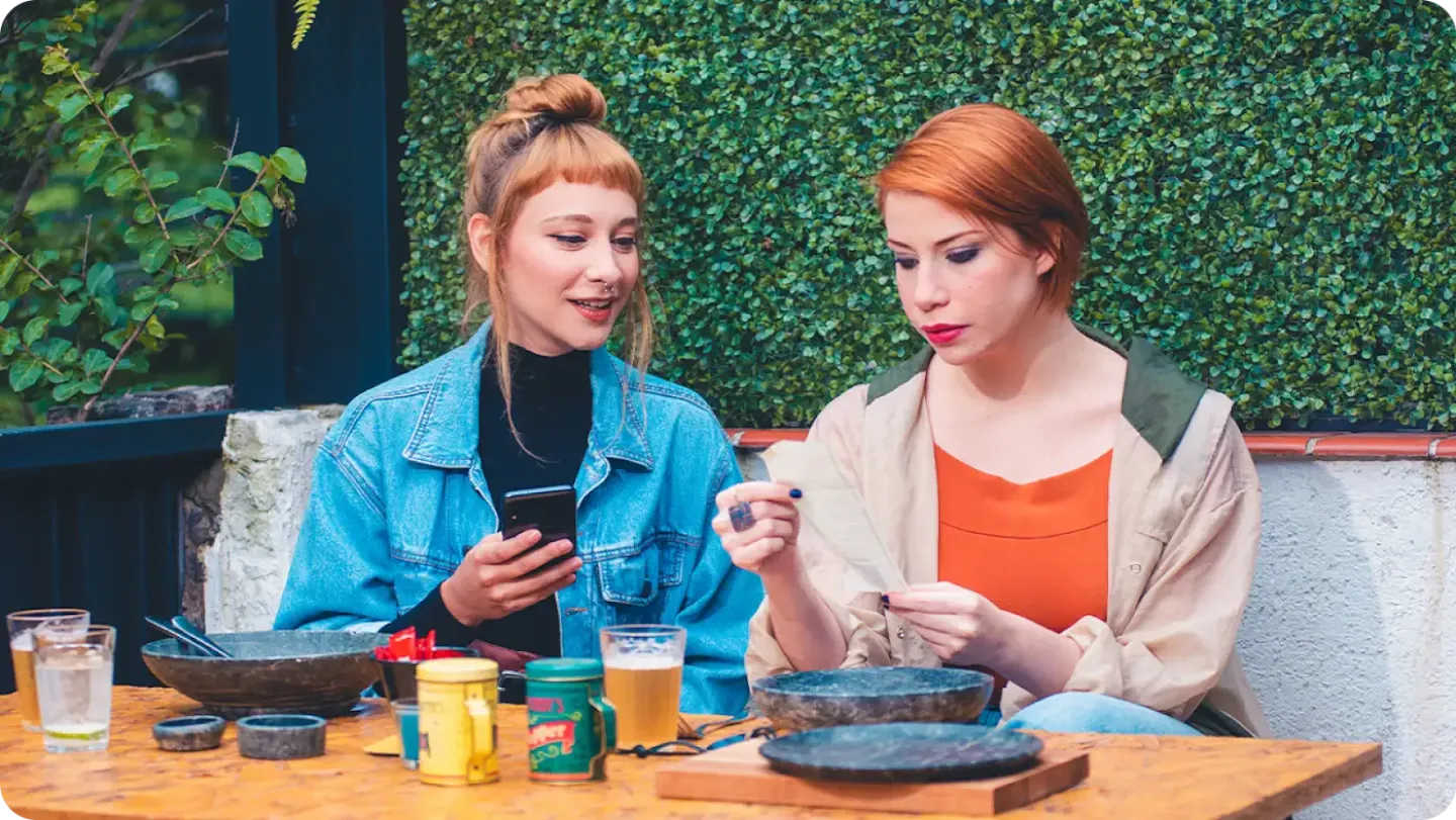 Two customers in a restaurant viewing their receipt after purchasing their meal using Tap and Pay.
