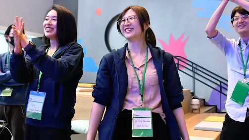 A group of people wearing ID badges are clapping.