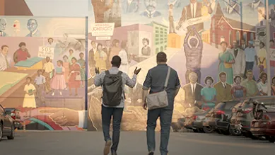Founders, Justin and Bernard, are walking in front of a mural.