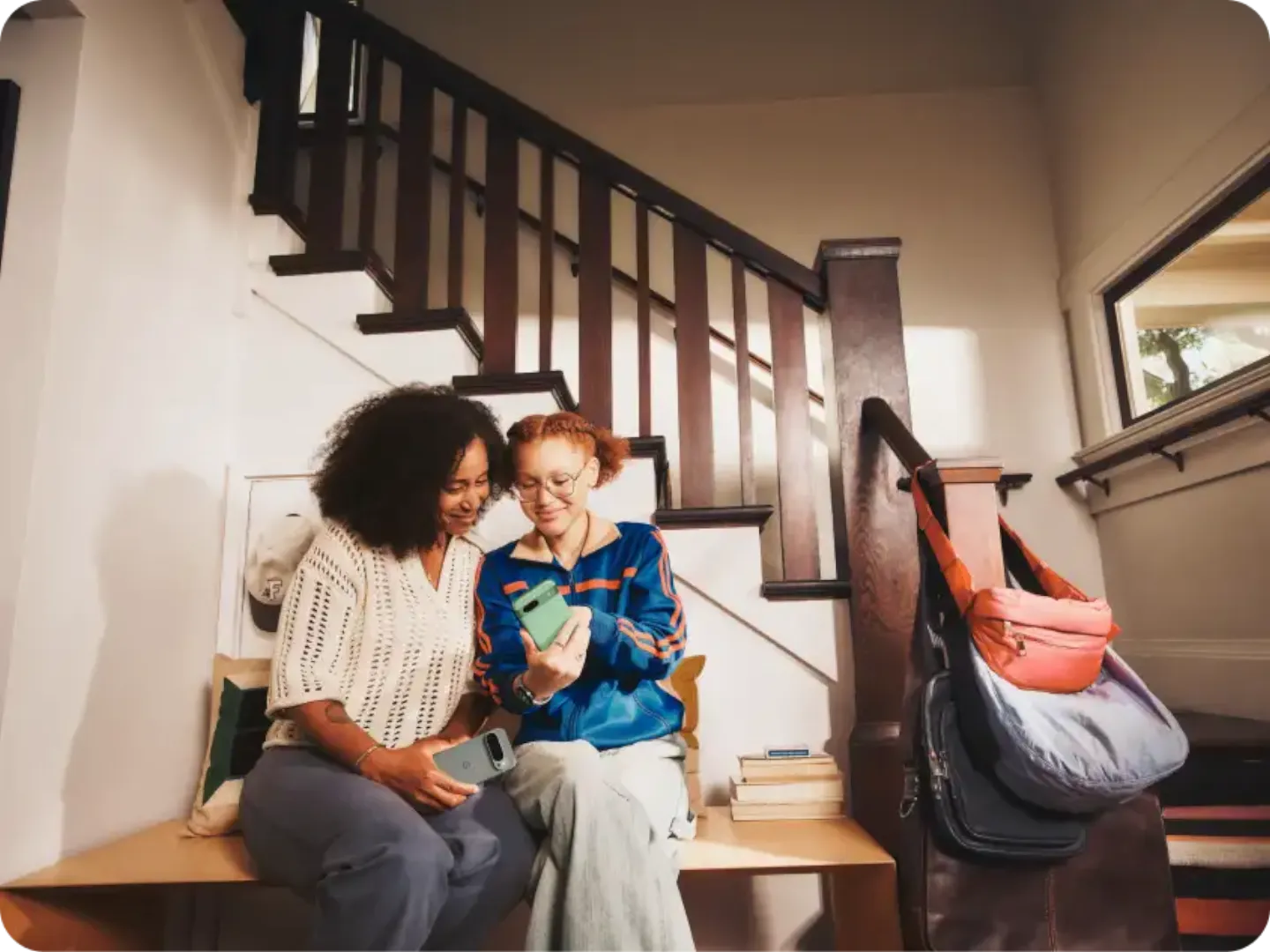 Woman and child sitting side-by-side, looking at a Pixel 9 phone, child pointing to a text message.