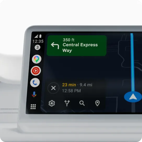 A black phone has “Android Auto” on its screen. Behind it is Google Maps on a car display.