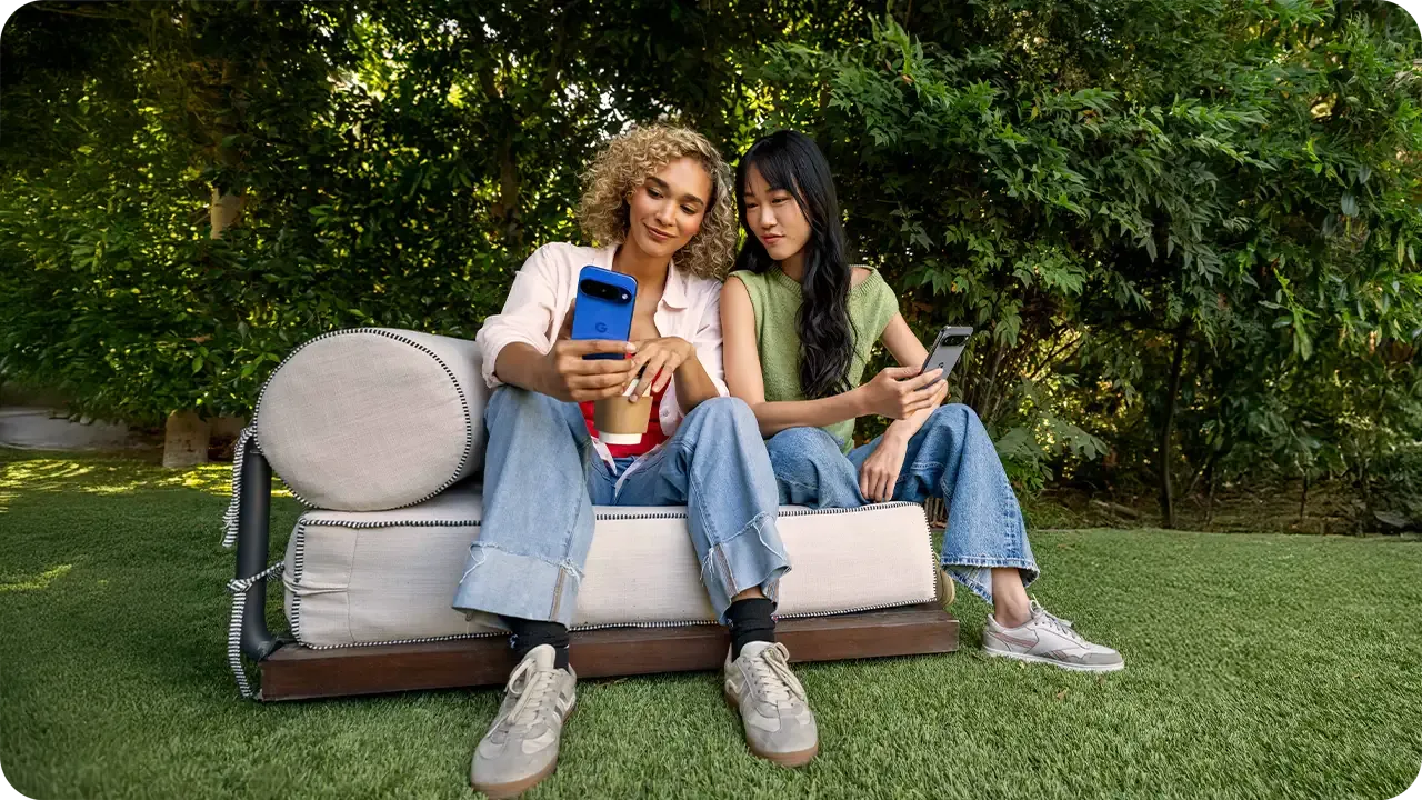 Women sitting outside on a garden, one of them is showing something on the screen of her smartphone to the other.