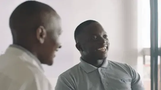 Founder, Gerald Otim, smiles at a table with colleagues.