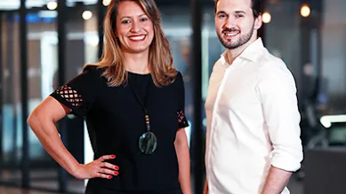 Founders Tatiana and Everton pose in front of an office space