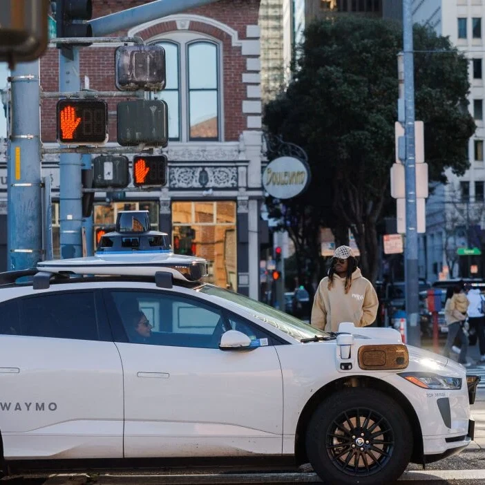 A waymo sits at a stop light in a city.