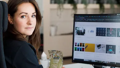 a woman operating a computer looking at the camera