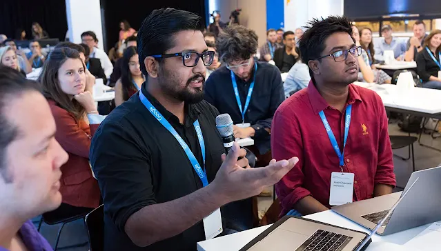An audience member with a mic questioning the host.