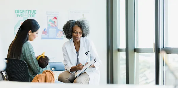 doctor going over paperwork with woman holding baby