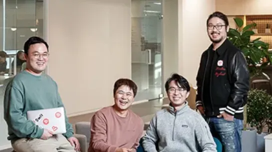 The Swit team are sitting around a couch smiling at the camera.