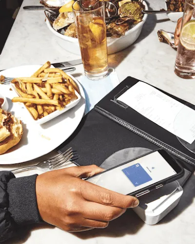 Half eaten hamburger and fries next to an open check at a restaurant