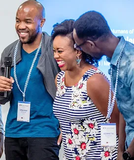 Three individuals are hosting an event, with one of them holding a microphone.