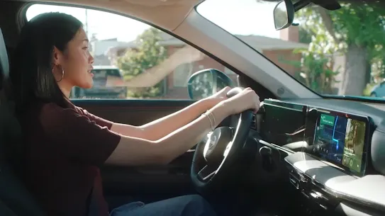 Woman driving a car with an electronic device on the dashboard, featuring a GPS map.