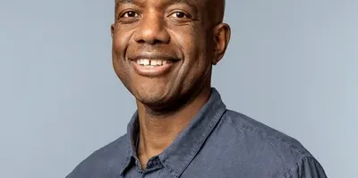 A headshot of James Manyika, Google’s SVP of Research, Labs, Technology & Society. He is wearing a dark blue, button-down collared shirt.