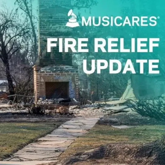 image of young man walking with guitar in hand in front of fire wreckage