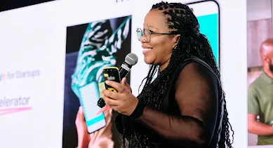 Com um microfone em uma mão e o celular na outra, a mulher conduz o evento e interage com o público.