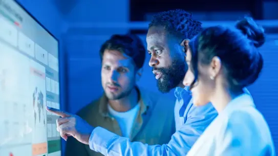 Three people reviewing data on a screen