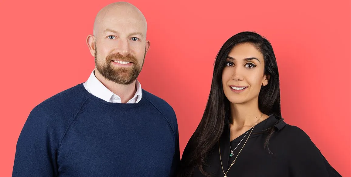Cofounders Peter Fish and Shardi Nahavandi smile at a camera against a pink backdrop.